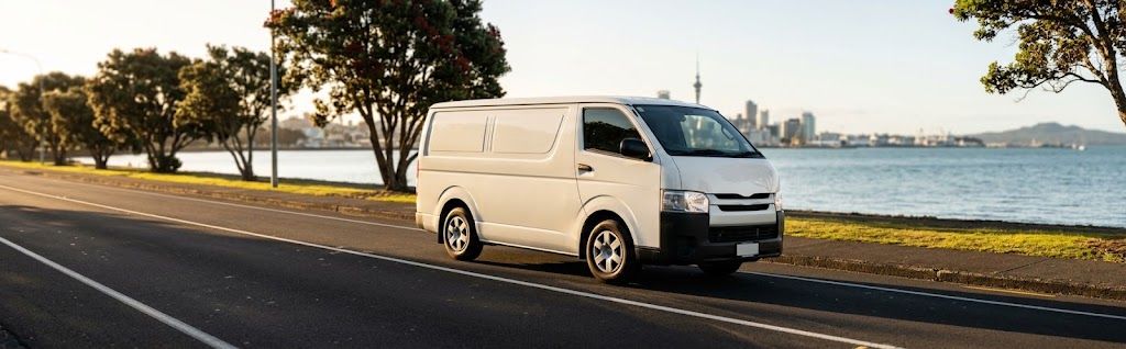 White delivery van driving along the Auckland waterfront with the city skyline behind